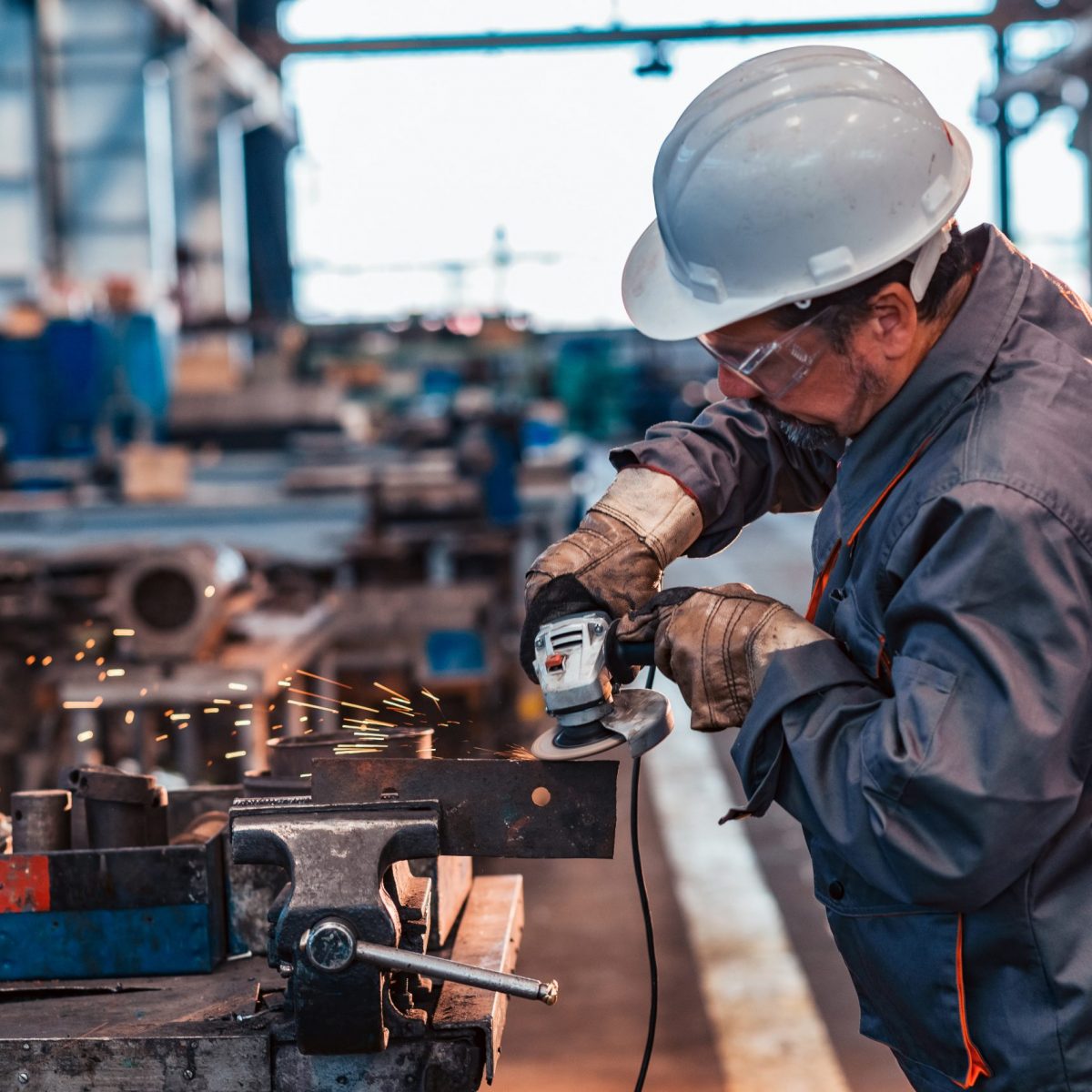 Skilled industrial worker grinding metal part.