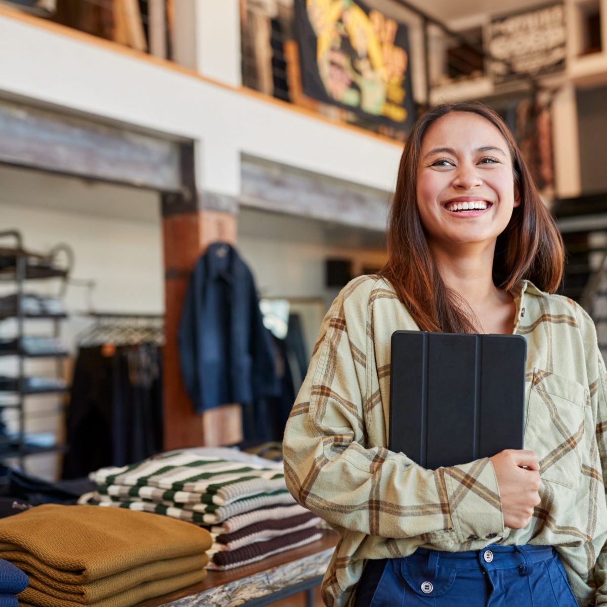 Portrait Of Female Owner Of Fashion Store Using Digital Tablet To Check Stock In Clothing Store